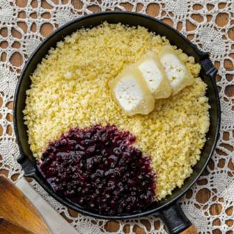 Rebel (Ribe) in Pfanne mit zerlassener Butter und Preiselbeeren, serviert auf gehäkelter Tischdecke – typische Speise aus Liechtenstein