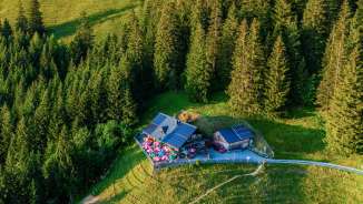Luftaufnahme der Gafadurahütte auf sonnigem Berghang, umgeben von Wäldern und Almwiesen in Liechtenstein