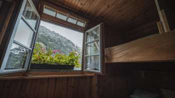 Fensterblick aus dem Schlafraum: Blick aus einem einfachen Schlafraum mit Stockbett der Gafadurahütte auf die Berglandschaft