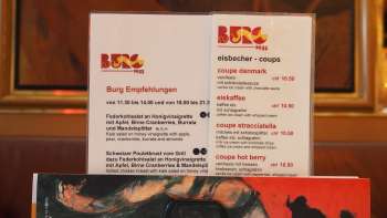 Brasserie Burg Speisekarte vor farbigem Wandbild – Kulinarik und Kunst im Herzen von Vaduz.