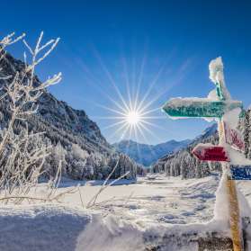 Verschneite Wegweiser und traumhafte Winterlandschaft bei strahlendem Sonnenschein in Steg, Liechtenstein.