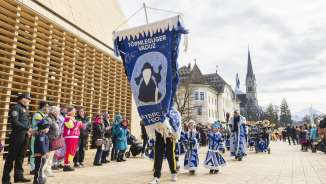 Festlich verkleidete Törmleguger Vaduz beim Fasnachtsumzug in Vaduz, Liechtenstein, vor Regierungsgebäude und Kathedrale.
