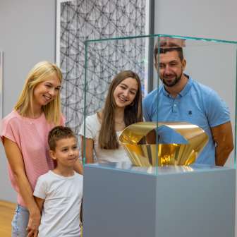Familie betrachtet eine goldene Skulptur im Kunstmuseum Liechtenstein – Kunstgenuss für Gross und Klein im Herzen von Vaduz.