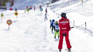 Skilehrer begleitet Kinder auf dem Übungslift in Malbun – ideales Skigebiet für Familien und Einsteiger in Liechtenstein.