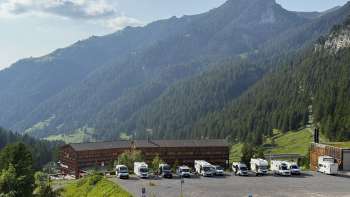 Mehrere Wohnmobile stehen auf dem sonnigen Stellplatz in Malbun mit Bergpanorama im Hintergrund