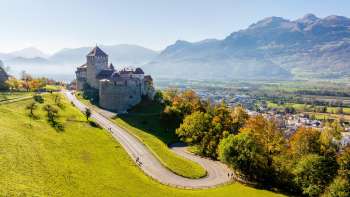 Schloss Vaduz auf einem Hügel mit Blick auf das Rheintal und umliegende Berge.