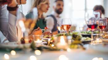 Stimmungsvolle Dinner Party: Menschen sitzen gemeinsam an einem festlich gedeckten Tisch und geniessen ein Abendessen