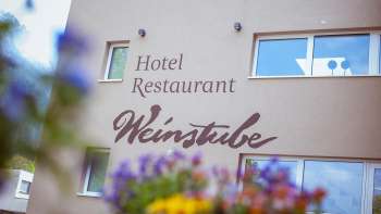 Aussenansicht des Restaurant Weinstube mit Blumen im Vordergrund 