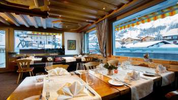 Heller, einladender Gastraum mit grosser Fensterfront und Blick auf schneebedeckte Berge