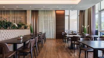 Modern eingerichtetes Restaurant Kommod mit dunklem Holzinterieur und gepolsterten Sitzbänken