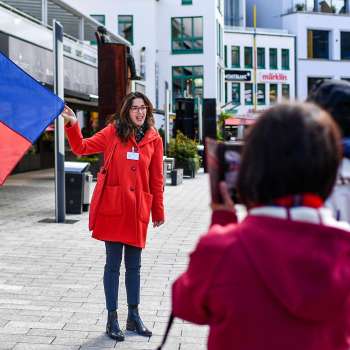 Stadtführerin mit Liechtenstein-Fahne begrüsst Touristengruppe in Vaduz