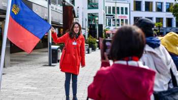 Stadtführerin mit Liechtenstein-Fahne begrüsst Touristengruppe in Vaduz