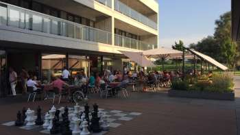 Gut besuchte Sonnenterrasse eines modernen Restaurants mit Grossschachfeld im Aussenbereich