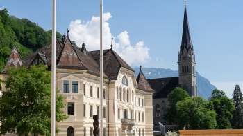  Blick durch einen Rundbogen auf das Regierungsviertel in Vaduz mit Landtagsgebäude und Kathedrale St. Florin.