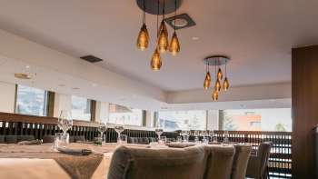 Modern eingerichteter Restaurantbereich mit Blick auf die Fensterfront und stilvollen Hängelampen.