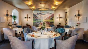 Eleganter Gastraum mit stilvoll gedeckten Tischen, edlem Ambiente und großem Landschaftsbild