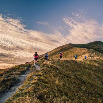 Gruppe von Trailrunnern auf einem Bergrücken bei Malbun, Liechtenstein, im Abendlicht