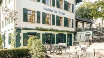Einladende Terrasse mit Holztischen und -stühlen vor dem Gasthaus zum Hirschen