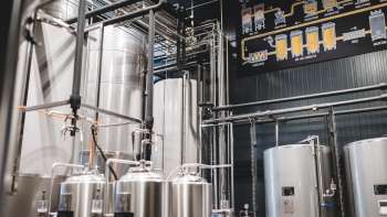 Blick in den Technikraum der Brauerei mit komplexem Leitungssystem und modernen Edelstahltanks.