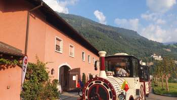 Citytrain steht vor der historischen Hofkellerei in Vaduz, bereit zur Abfahrt.