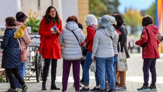 Führung City-ClassicTour im Städtle Vaduz Reisegruppe mit Stadtführerin in rotem Mantel bei einer geführten Tour durch das Zentrum von Vaduz in Liechtenstein