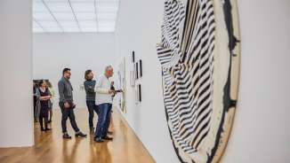 Besucher betrachten moderne Kunstwerke in einer Galerie des Kunstmuseums Liechtenstein mit heller Architektur und Holzfußboden