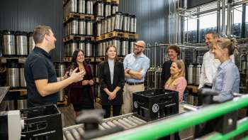 Besuchergruppe bei einer Führung durch das Fasslager der Brauerei mit Erklärungen eines Brauereimitarbeiters.