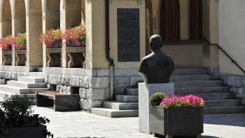 Blick auf den Eingangsbereich des Rathauses Vaduz mit Blumenarrangements, historischer Büste und breiten Steinstufen – ein kulturelles Wahrzeichen im Zentrum von Vaduz.