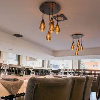 Modern eingerichteter Restaurantbereich mit Blick auf die Fensterfront und stilvollen Hängelampen.