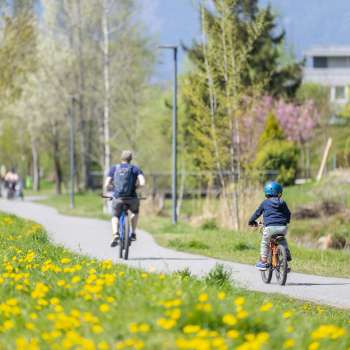 Familie radelt auf dem Frühlingsradweg im Naturpark Haberfeld, umgeben von blühenden Wiesen und Bäumen.