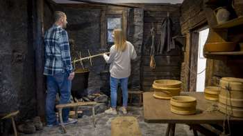 Besucher erkunden eine alte Rauchküche im Walsermuseum Triesenberg