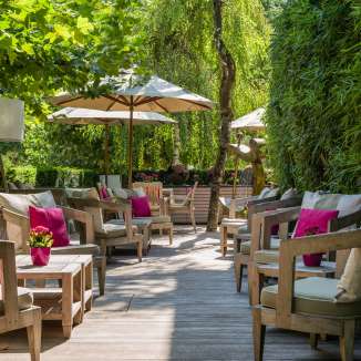 Bequeme Sitzgruppe mit Kissen, Pflanzen und Sonnenschirmen auf der Terrasse des Park Hotel Sonnenhof in Vaduz, Liechtenstein