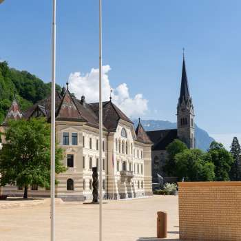  Blick durch einen Rundbogen auf das Regierungsviertel in Vaduz mit Landtagsgebäude und Kathedrale St. Florin.