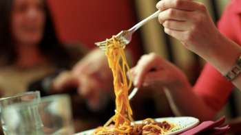Person hebt mit der Gabel Spaghetti von einem Teller in der Brasserie Burg – italienischer Genuss in geselliger Atmosphäre.