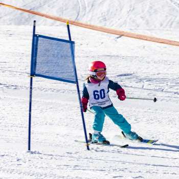 Kleines Kind mit Startnummer fährt konzentriert beim Kinderskirennen im Malbi-Park Malbun durch die Tore.