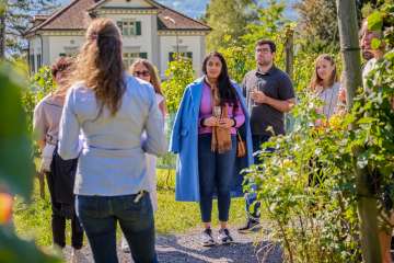 Eine Gruppe nimmt an einer geführten Weinverkostung in den Weinbergen der Hofkellerei in Vaduz teil, inklusive Degustation regionaler Tropfen