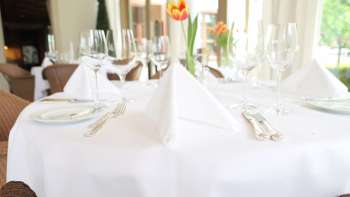 Festlich gedeckter Tisch mit weisser Tischdecke und frischer Tulpe