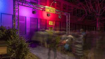 Eingangsbereich des Kleintheaters Schlösslekeller bei Nacht mit farbiger Beleuchtung und Publikum