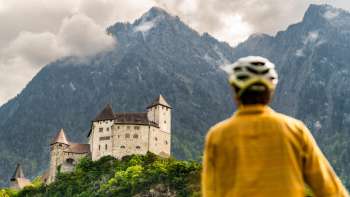 Mountainbiker in gelber Jacke blickt auf die Burg Gutenberg