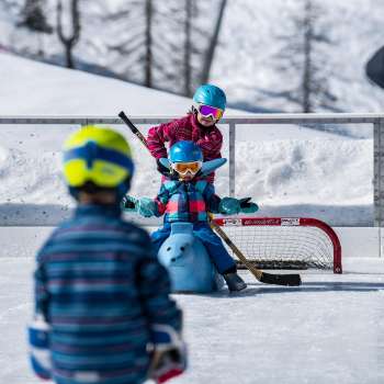 Familie beim Schlittschuhlaufen und Eisstockschiessen in Malbun