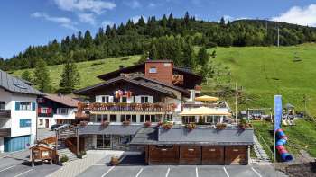 Außenansicht des Restaurants Turna bei grünem Hang mit Sommerterrasse und blühenden Pflanzen. Außenansicht des Restaurants Turna bei grünem Hang mit Sommerterrasse und blühenden Pflanzen.