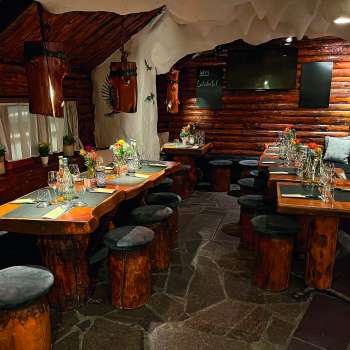 Blick auf ein rustikal eingerichtetes Restaurant mit Holzmöbeln, grün dekorierten Tischen und Kerzen.