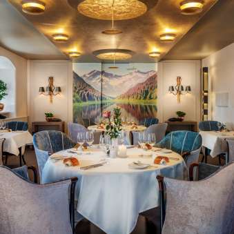 Rund gedeckte Tische mit Weingläsern und Kerzen im eleganten Speisesaal des Park Hotel Sonnenhof in Vaduz, Liechtenstein