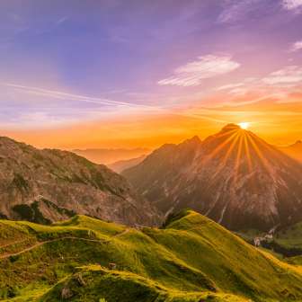 Sonnenuntergang hinter den Berggipfeln bei Malbun in Liechtenstein mit Almen, Bergwegen und goldenem Licht