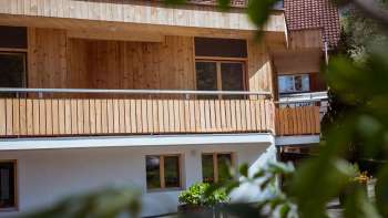 Außenansicht des Gästehauses beim Camping Mittagsspitze mit Holzfassade und Balkon in naturnaher Umgebung.