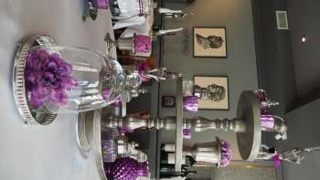 Tischdekoration mit lilafarbenen Blumen auf weisser Tischdecke