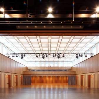 Großer Veranstaltungssaal mit Holzverkleidung, Bühne und Beleuchtung in Schaan, Liechtenstein – geeignet für Events, Konferenzen und Konzerte