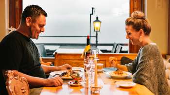 Paar genießt ein gemütliches Abendessen bei Kerzenschein und Blick auf den Außenbereich