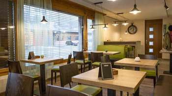 Modernes Bistro mit gemütlichem Ambiente, Holztischen und stilvollen grünen Sitzbänken