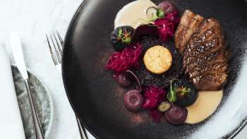 Stilvoll angerichtetes Essen auf schwarzem Teller im Chapter Two